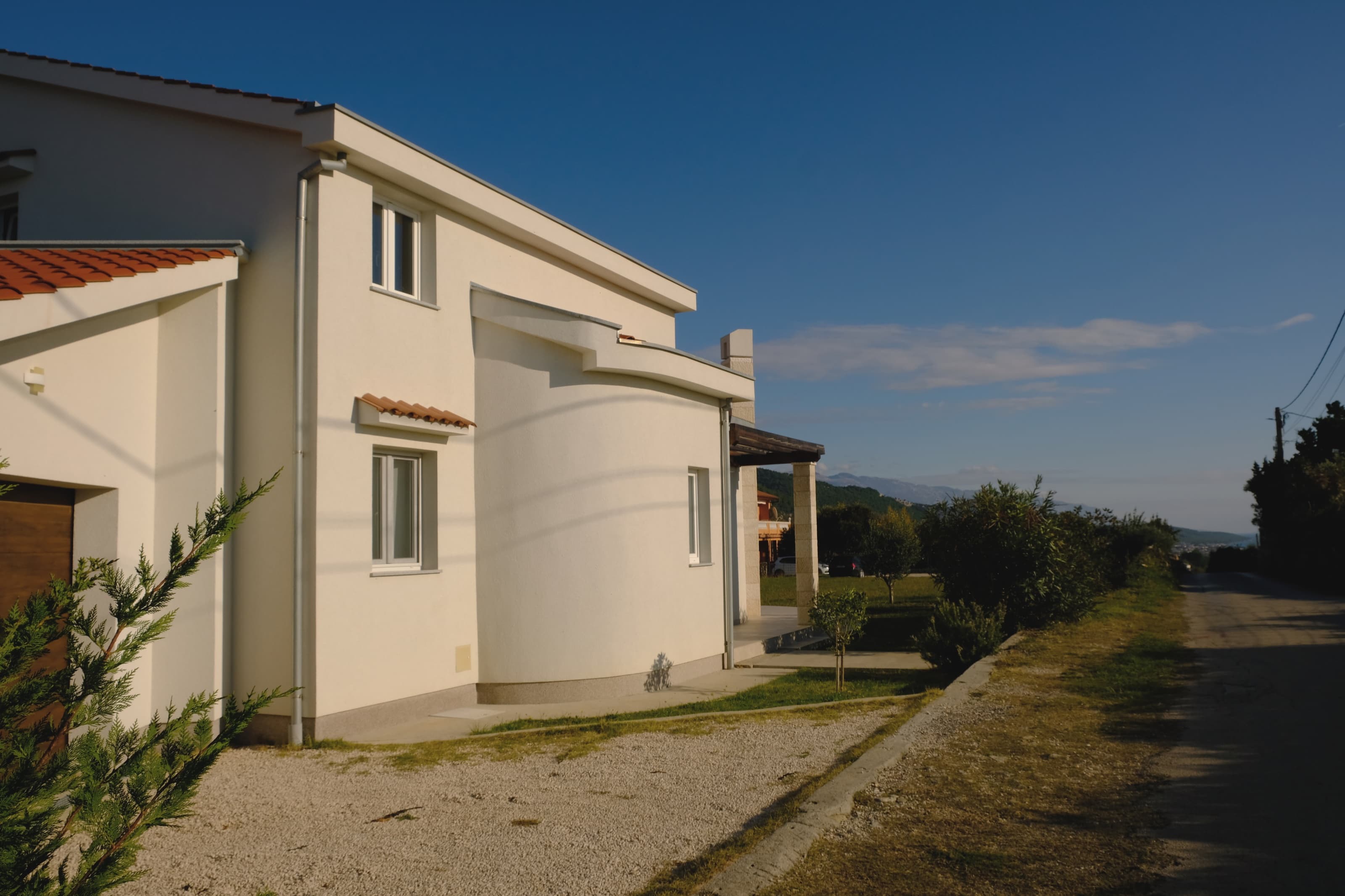 Ein sonniges Inselhaus, Garten und eine ruhige Seitenstraße.
