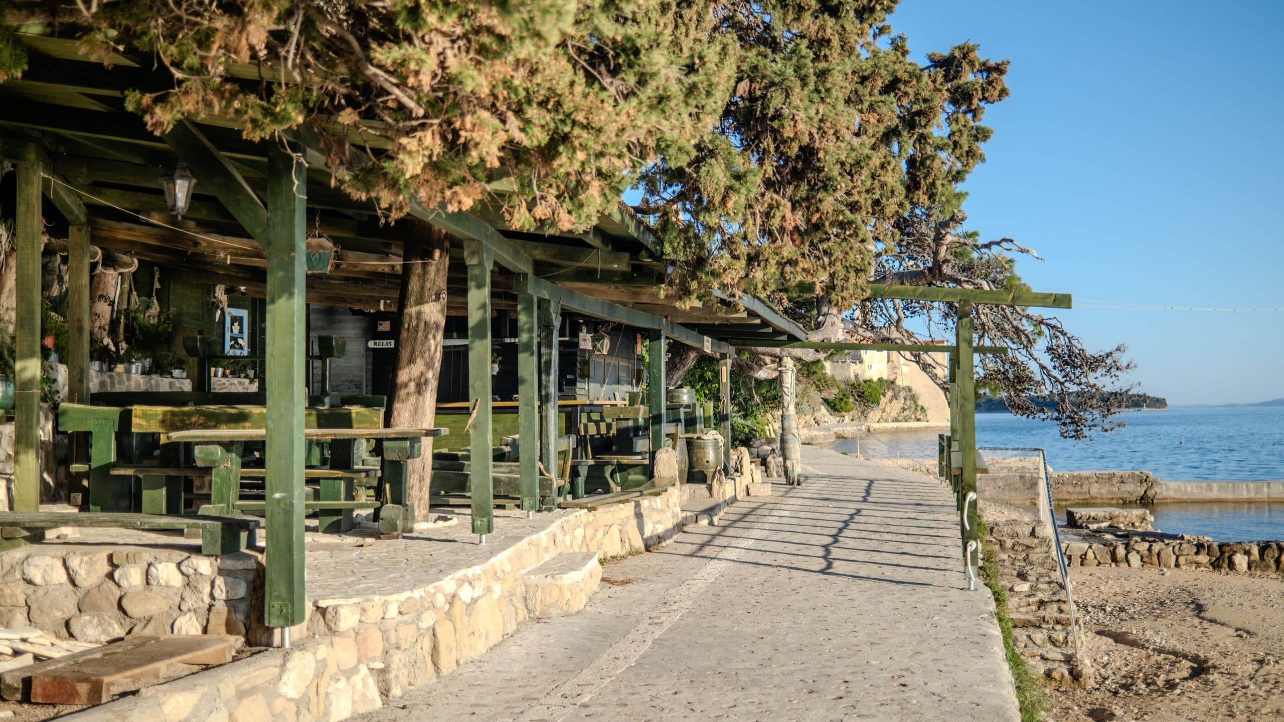 A seaside konoba on the waterfront promenade — the path to dinner at last light.